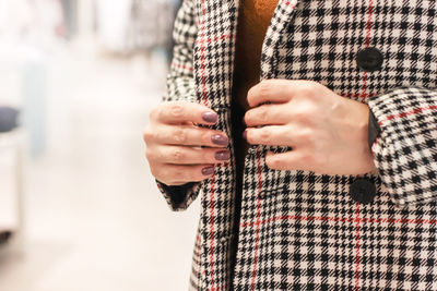 Close-up midsection of woman wearing check patterned overcoat