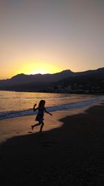 Silhouette man on beach against sky during sunset