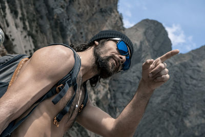 Shirtless man pointing against mountain