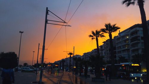 Cars on street against sky at sunset