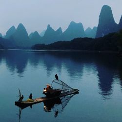 People in boat on lake against sky