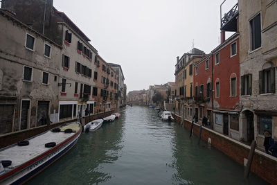 Canal amidst buildings in city against clear sky