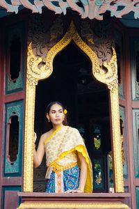 Young woman standing at window of building