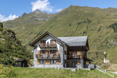 Houses on field by mountain against sky