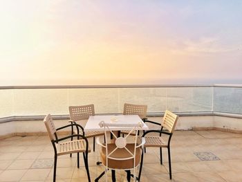 Chairs and table by sea against sky