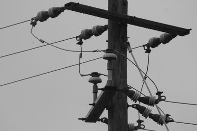 Low angle view of bird perching on cable against sky