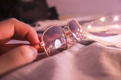 Close-up of hand holding eyeglasses on table