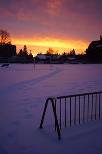 Scenic view of snow covered landscape against orange sky