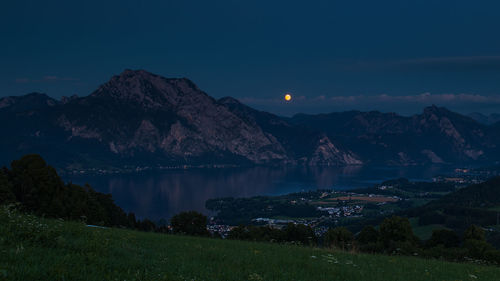 Scenic view of lake by mountains against sky at night