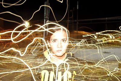 Portrait of woman with illuminated lighting equipment at night