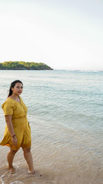 Full length of woman standing on beach against sky