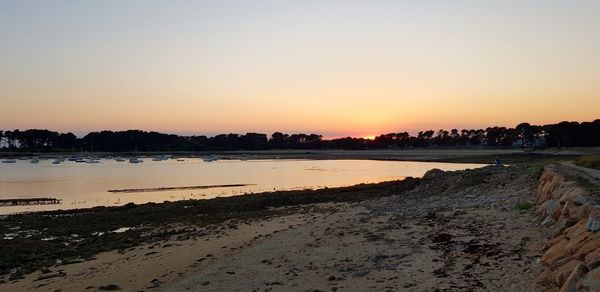 Scenic view of beach against clear sky during sunset