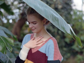 Young woman looking away while standing outdoors