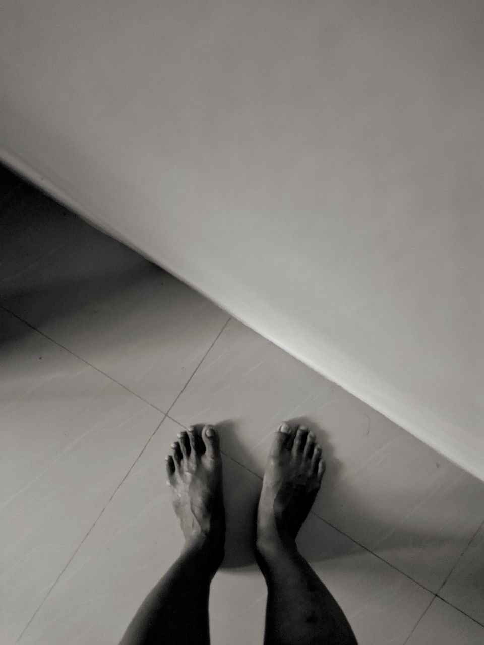 LOW SECTION OF WOMAN LEGS ON TILED FLOOR