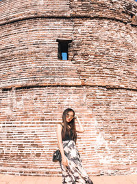 Portrait of woman standing against brick wall