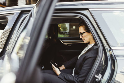 Entrepreneur using smart phone while sitting in car
