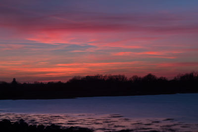 Scenic view of lake against orange sky