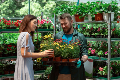 Portrait of smiling young woman standing in greenhouse