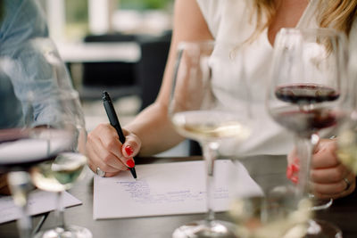 Midsection of woman holding wine glass on table
