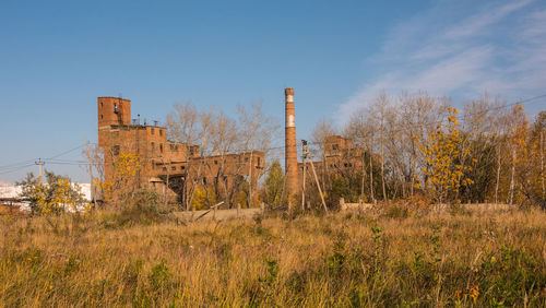 Abandoned factory on field against sky