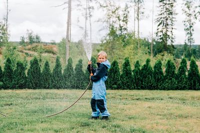 Full length of boy standing on grass against trees