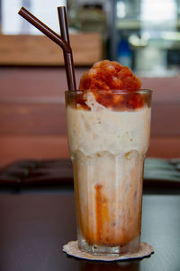 Close-up of ice tea served in glass on wooden table