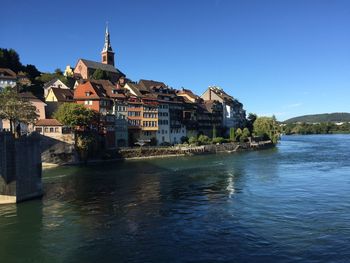 Buildings at waterfront against blue sky