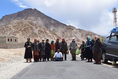 People on mountain road against cloudy sky