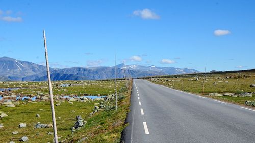 Road leading towards mountains against sky