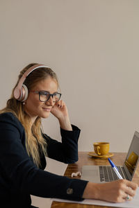 Woman working at home with laptop and papers on desk and headphones. home office . gray notebook 