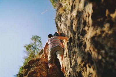 Rear view of man on rock against sky