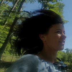 Close-up of young woman against trees