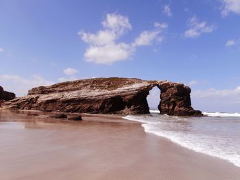 Rock formation on beach against sky