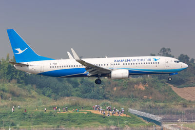 Airplane flying over airport runway against clear sky