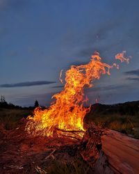 Bonfire on wooden structure in field against sky