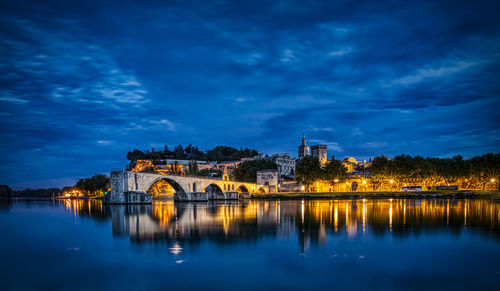 Illuminated bridge over river against sky at night