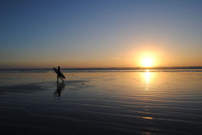 Silhouette man on beach against sky during sunset