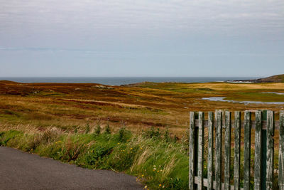 Scenic view of landscape by sea against sky