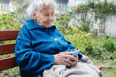 Senior mature woman, grandmother holding phone, using mobile device apps, looking at screen