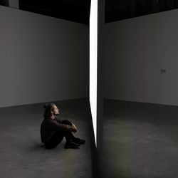 Man sitting on floor against wall at home