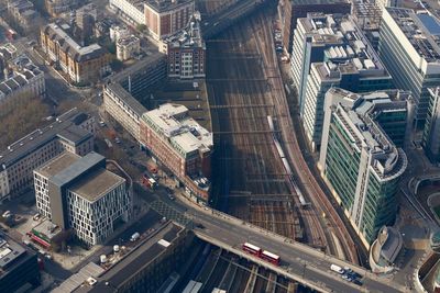 Aerial view of bridge over railroad tracks amidst buildings on sunny day in city