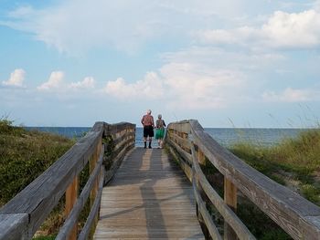 Rear view of people walking on pier