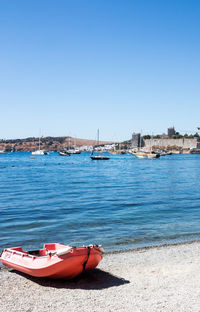 Boats moored on sea against clear blue sky