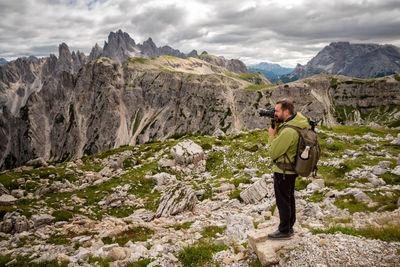 Photographer with telephoto lens in mountain landscape. man with mountain trekking sportswear