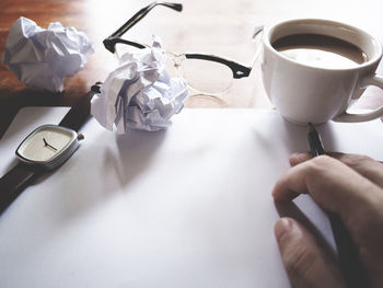 Close-up of hand holding coffee cup on table