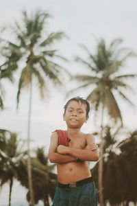 Portrait of a boy standing against palm trees