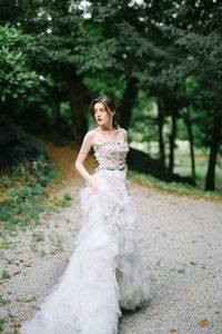 Portrait of woman with arms outstretched against trees