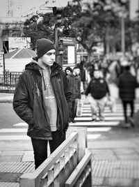 Boy standing by railing in city