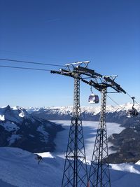 Ferris wheel against snowcapped mountains against clear blue sky