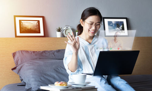 Young woman using phone while sitting on table at home